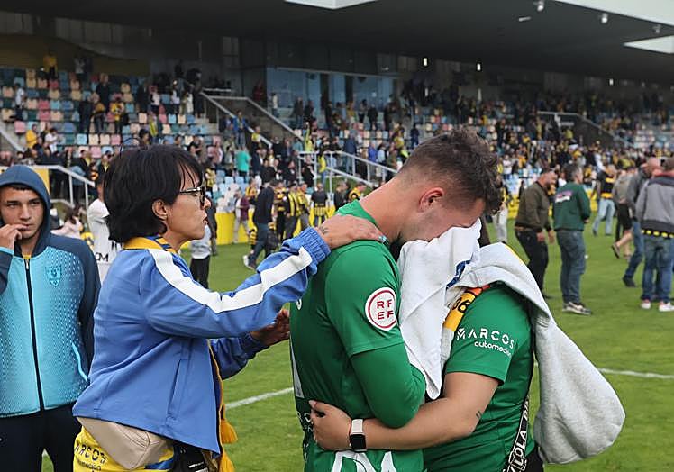 Dos aficionadas escorpiones consuelan a Aitor por la pérdida del ascenso con el Barakaldo en Lasesarre.