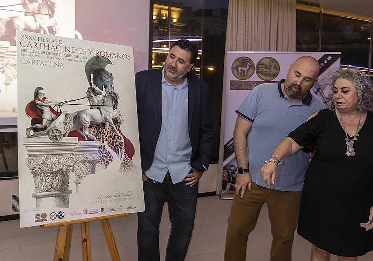 José Antonio Meca, junto al cartel y dos festeros.