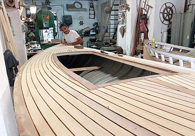 Rafa, el hijo de Pepe El Calafate, calafatea las costuras de las tablas que hay sobre la cubierta.
