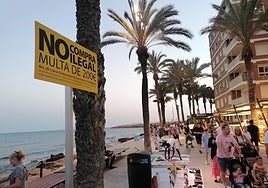 Los 'manteros' colocan sus productos a escasos metros del cartel que avisa de que la compra de los mismos está penada con multas de 200 euros.