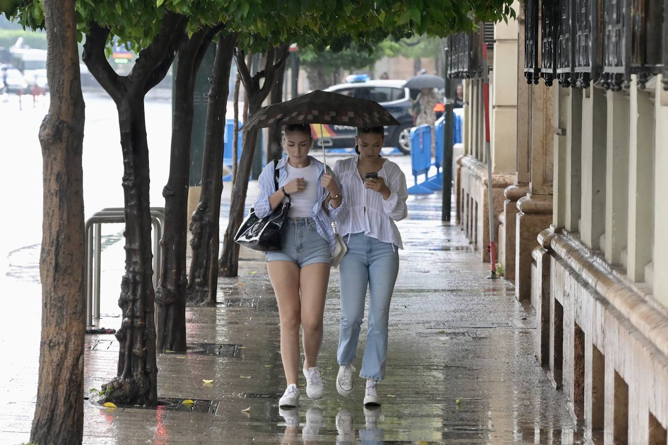 Dos jóvenes se protegen de la lluvia con un paraguas en el centro de Murcia, en una imagen de archivo.