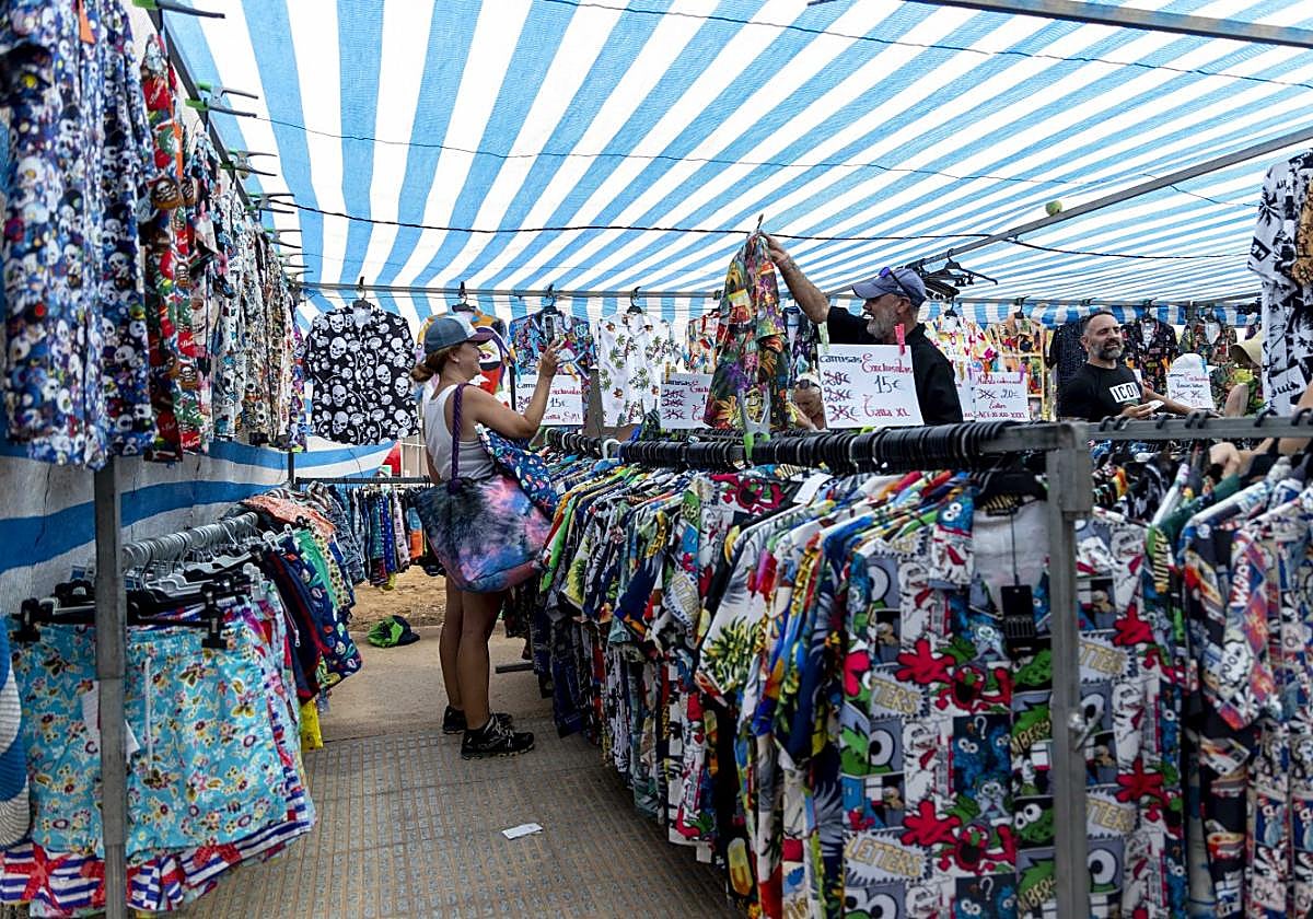Varias personas echan un vistazo a la ropa de uno de los puestos del mercadillo de venta ambulante de Cabo de Palos este domingo.
