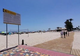 Un grupo de bañistas camina sobre la nueva pasarela sobre la desembocadura del río Nacimiento en Campoamor.