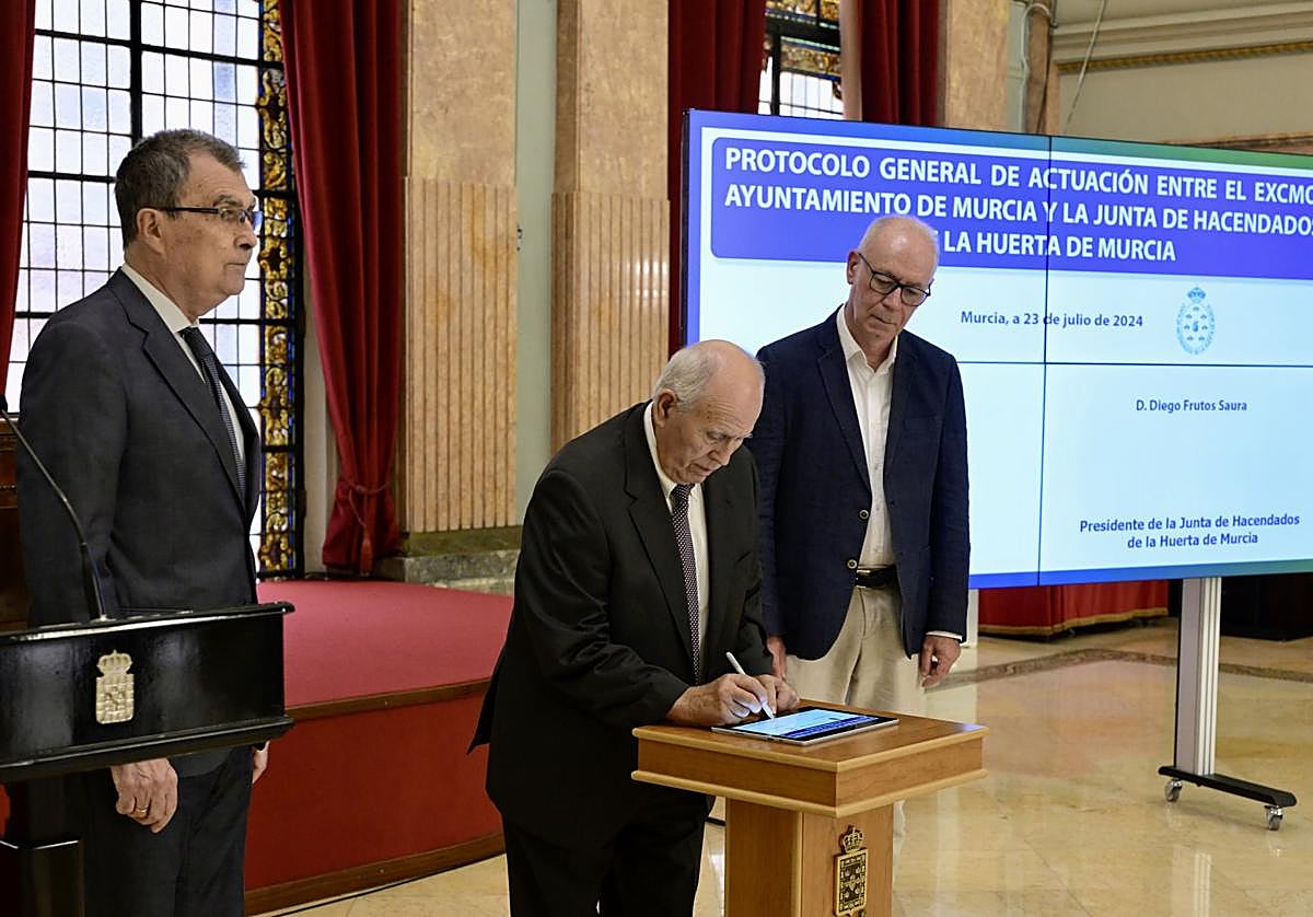 Diego Frutos firma el nuevo protocolo, en presencia del alcalde Ballesta y el concejal Navarro Corchón.