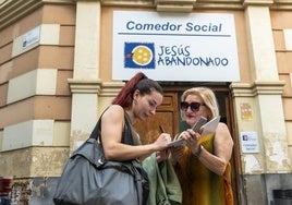 Mari Belmonte recoge firmas a las puertas del comedor social de Jesús Abandonado para pedir la reapertura del centro de reducción de daños cerrado.