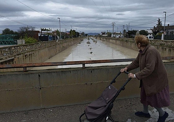 Acostumbrados. Una vecina cruza el puente sobre el Reguerón en la pedanía de Beniaján durante una crecida en 2016, en una instantánea de Guillermo Carrión.