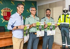 Dos agentes de la Guardia Civil posan con el cartel de la carrera solidaria.