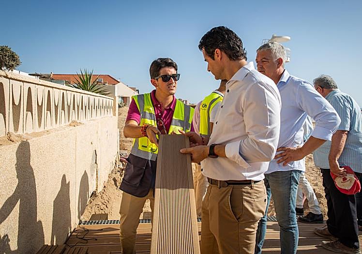 Un trabajador de Orthem muestra el material del que está hecho el nuevo pavimento de la senda.