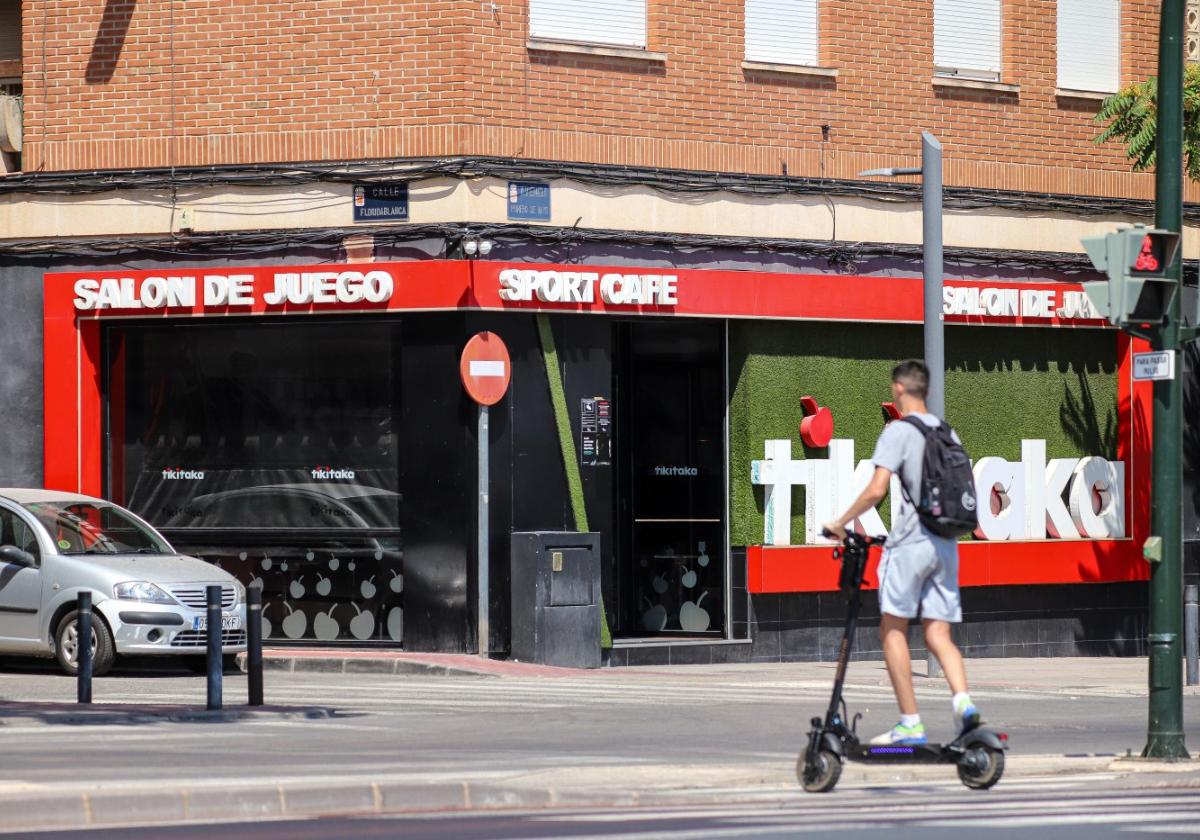 Un joven circula con un patinete, ayer, frente a un salón de juego de la ciudad de Murcia.