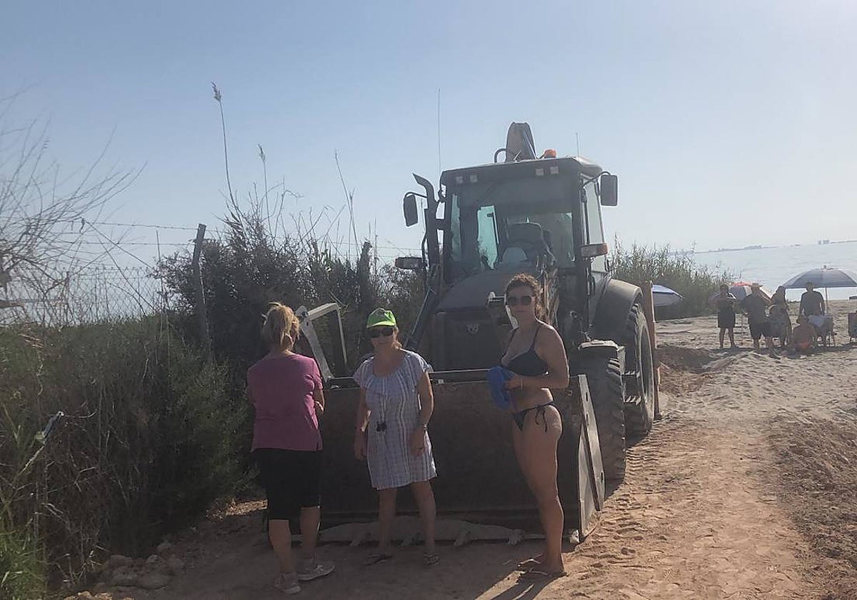 Tres vecinas delante de un tractor, en el playa de Bahía Bella.