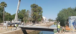 Operarios trabajando en la reparación del puente peatonal sobre el canal del Acequión.