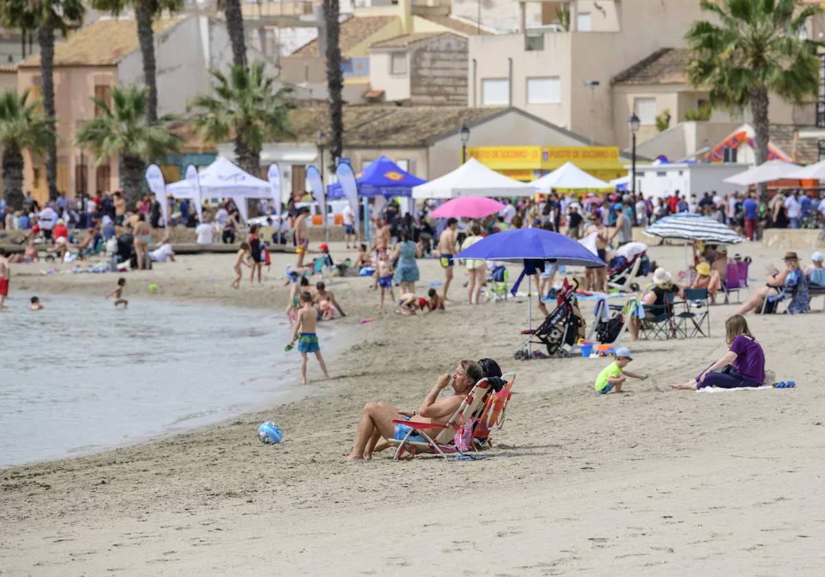 Vecinos y visitantes, tomando el sol en una playa de Los Alcázares.
