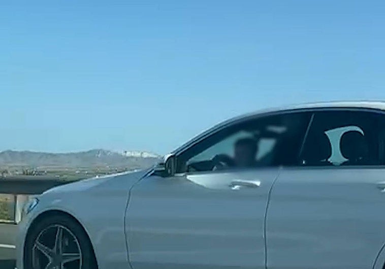 El menor sobre el regazo del conductor del vehículo.