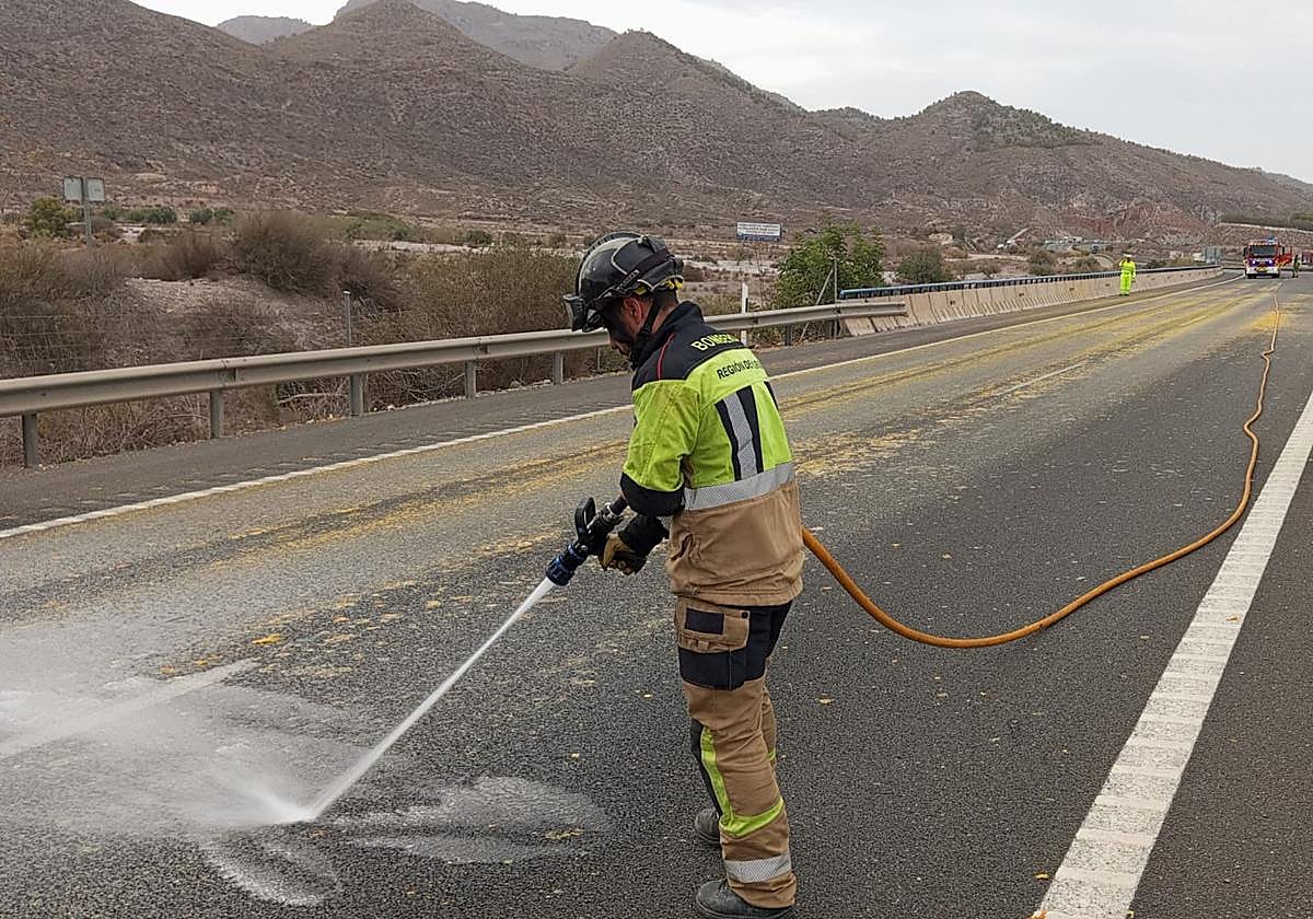 Un bombero limpia la calzada, tras la caída del cargamento de naranjas.