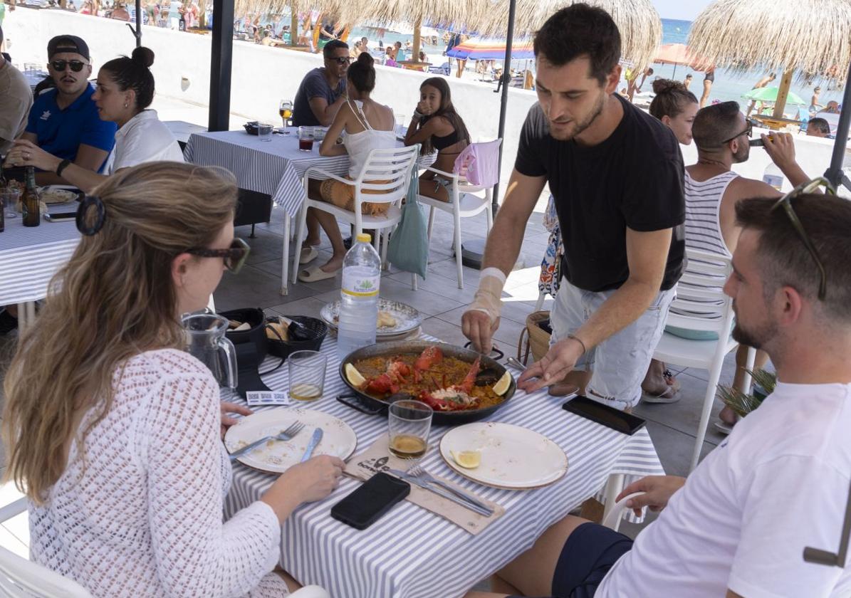 Un camarero sirve un arroz a una pareja, en un restaurante a pie de playa en La Manga.