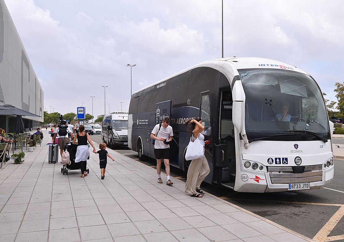 Imagen secundaria 1 - Arriba: Un taxi se mete hasta la puerta de entrada del aeropuerto para recoger a un pasajero en plena granizada. Abajo izq.: El autobús directo al aeropuerto desde Murcia y Cartagena, con pocos viajeros de manera «habitual». Abajo der.: Varios pasajeros se dirigen a los controles de seguridad previos al acceso a la zona de embarques.