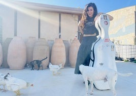 Julia Casado, en su bodega modular, con su violonchelo y rodeada de animales.