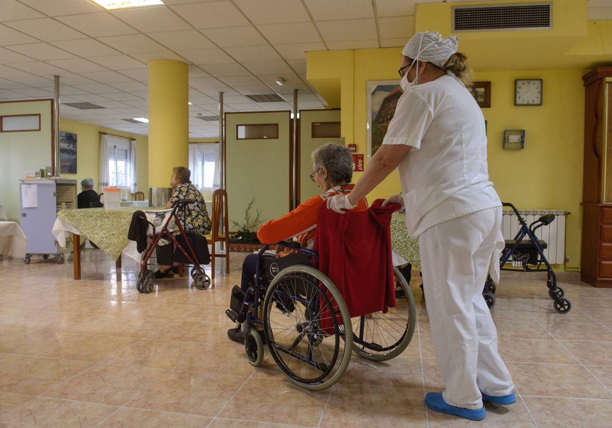 Una sanitaria traslada a una anciana en una residencia de mayores de Murcia.