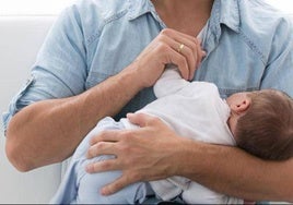 Un padre con su bebé en brazos.