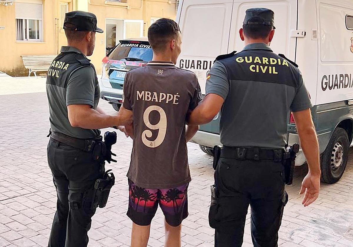 Dos agentes trasladan al presunto autor del robo en el aserradero de Moratalla.