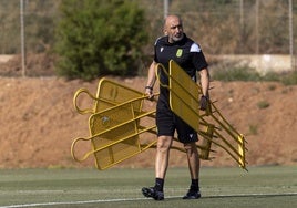 El entrenador del Cartagena, Abelardo Fernández, carga las barreras de plástico antes de un entrenamiento en La Manga Club.