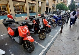 Varias motos de Gougo Motosharing estacionadas en un aparcamiento de ciclomotores.