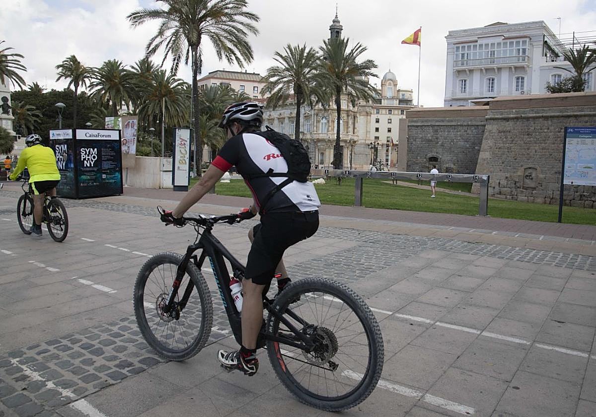 Dos ciclistas circulan por el carril bici del Paseo Alfonso XII, frente a lo que fue el aparcabicis del servicio de alquiler de estos vehículos, que dejó de prestarse hace una década.