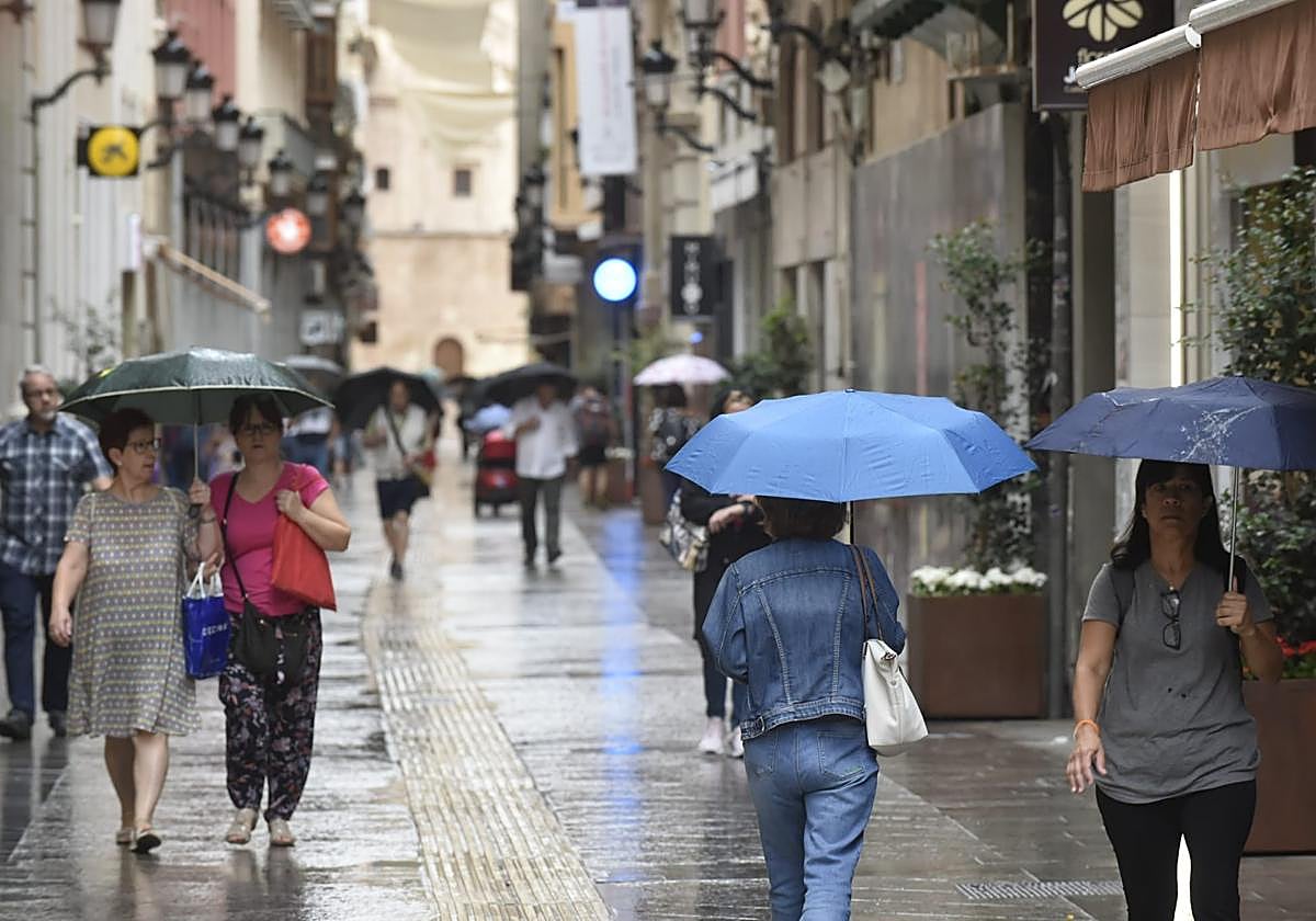 Viandantes con paraguas en el centro de Murcia, este jueves.