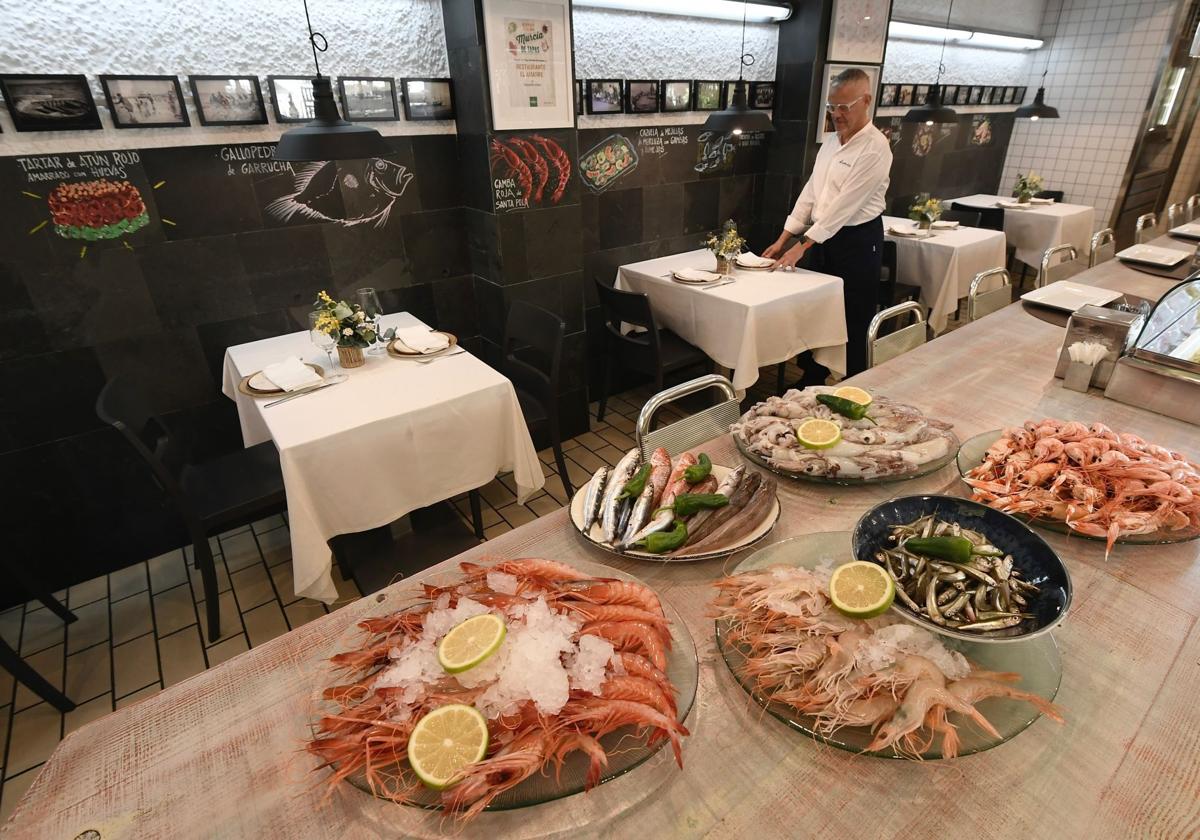 Preparación de las mesas en el restaurante, con algunos de los mariscos y pescados en la barra.