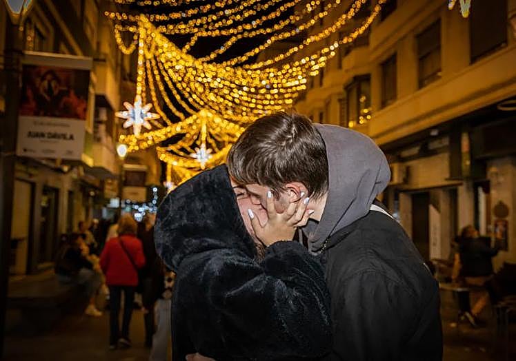 Una pareja se besa en la calle Concepción, durante la fiesta del encendido de las luces de Navidad en Torrevieja.