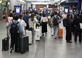 Varias personas esperan la salida de su tren en la estación de Atocha en Madrid este domingo.