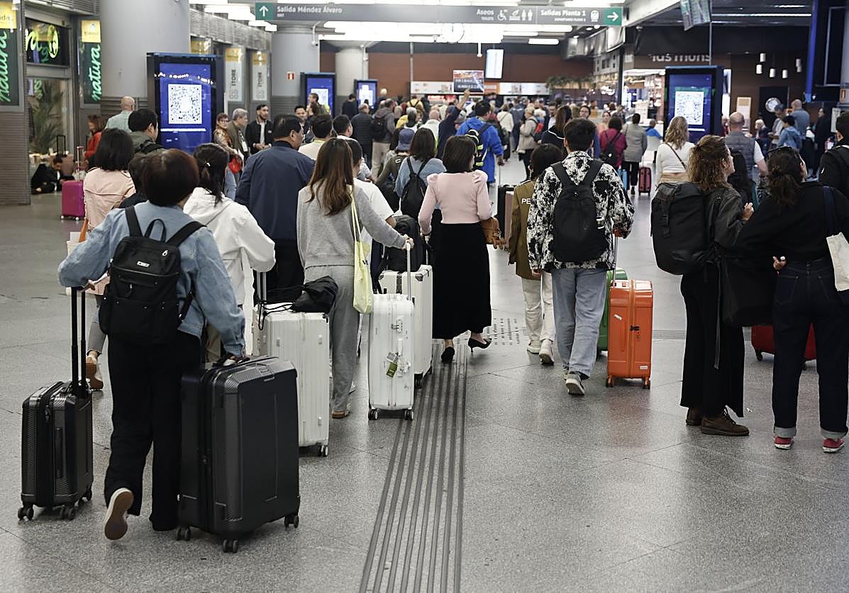 Varias personas esperan la salida de su tren en la estación de Atocha en Madrid este domingo.