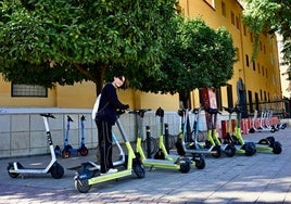 Un usuario toma un patinete de alquiler de entre la veintena de los ubicados en un momento de esta semana en la plaza Universidad.