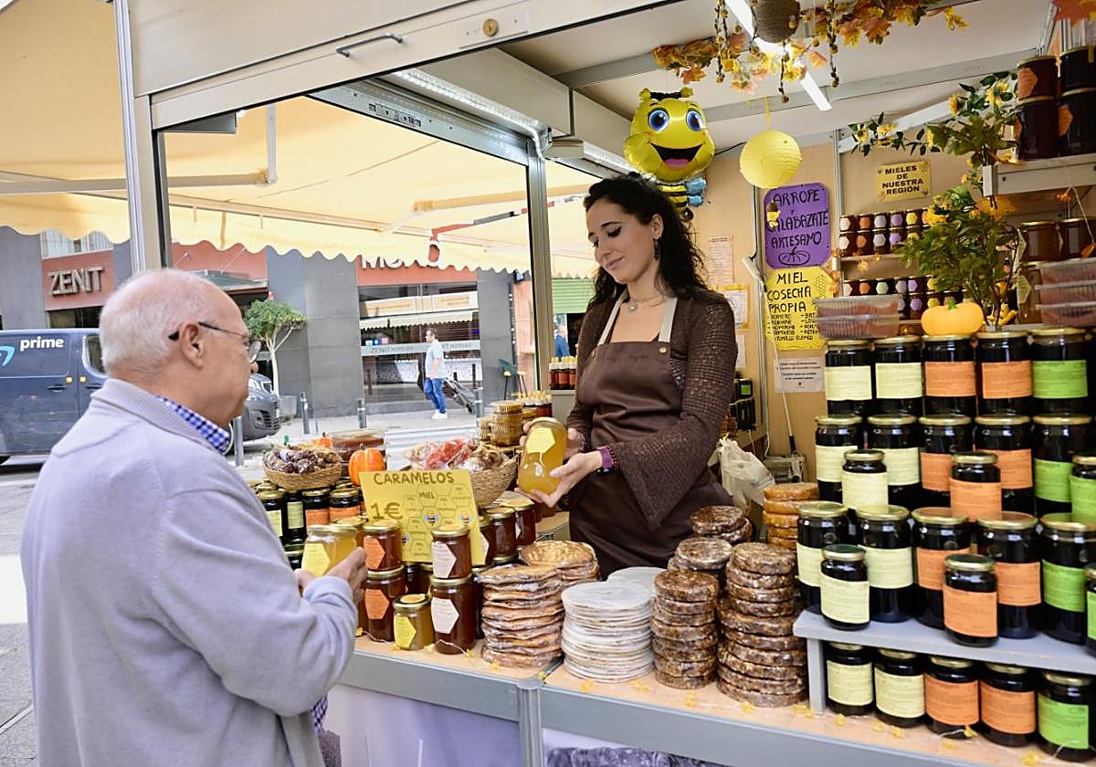 Sara Miñano muestra un bote de miel a un cliente en el estreno del Mercado de Todos los Santos.