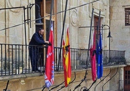 uUn funcionario municipal coloca crespones negros en las banderas del balcón principal del Ayuntamiento de Caravaca.