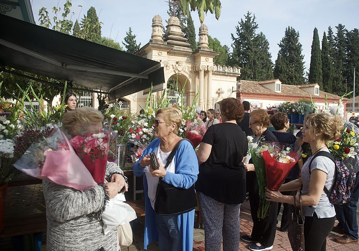 Varias personas compran flores a la entrada del cementerio Nuestro Padre Jesús, en Espinardo, por el Día de Todos los Santos.