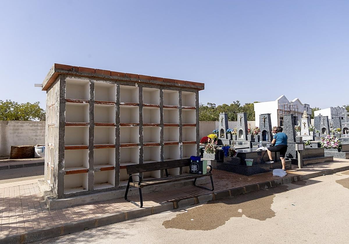 Una mujer limpia una tumba de su propiedad, junto los 80 columbarios del cementerio municipal de San Antón, este jueves.