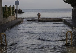 Dos vecinos pasan por la desembocadora de la rambla de las Moreras de Mazarrón, este domingo.
