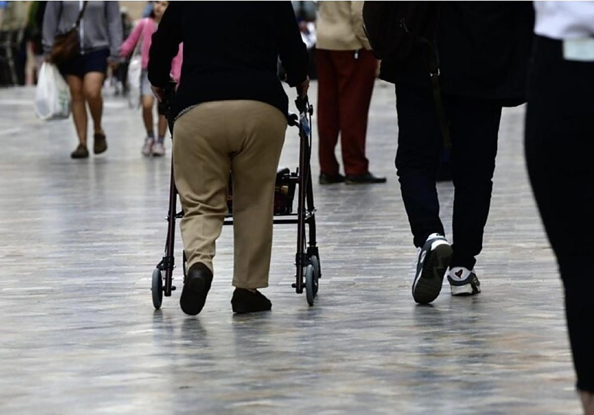 Una persona dependiente camina con andaderas por el centro de la ciudad.