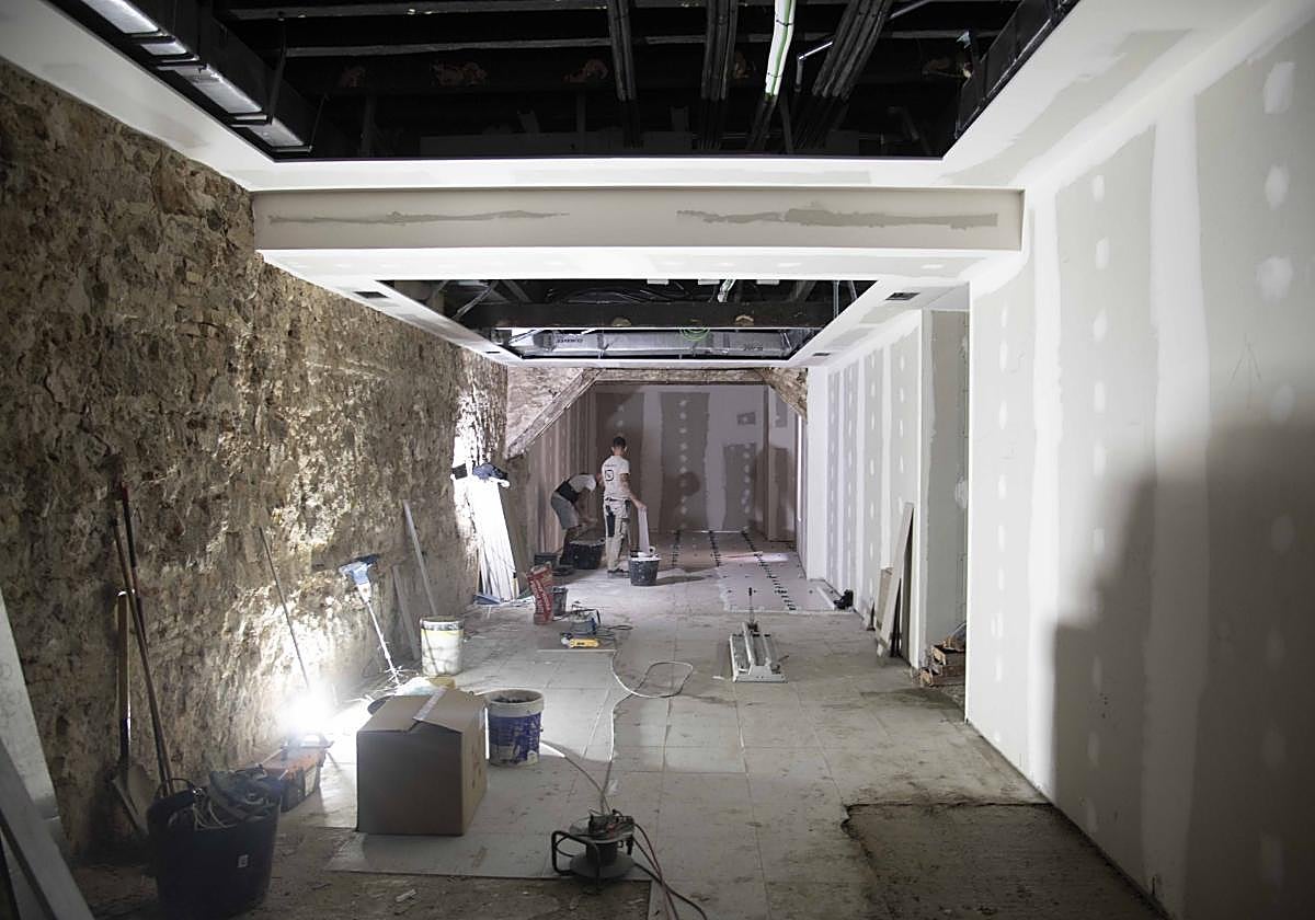 Dos albañiles instalan el suelo, en lo que será la sala expositiva.