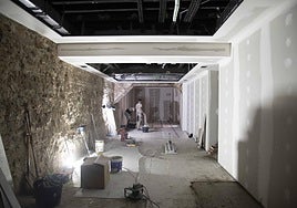 Dos albañiles instalan el suelo, en lo que será la sala expositiva.