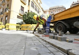 Un obrero limpiando uno de los imbornales de la plaza de los Apóstoles.