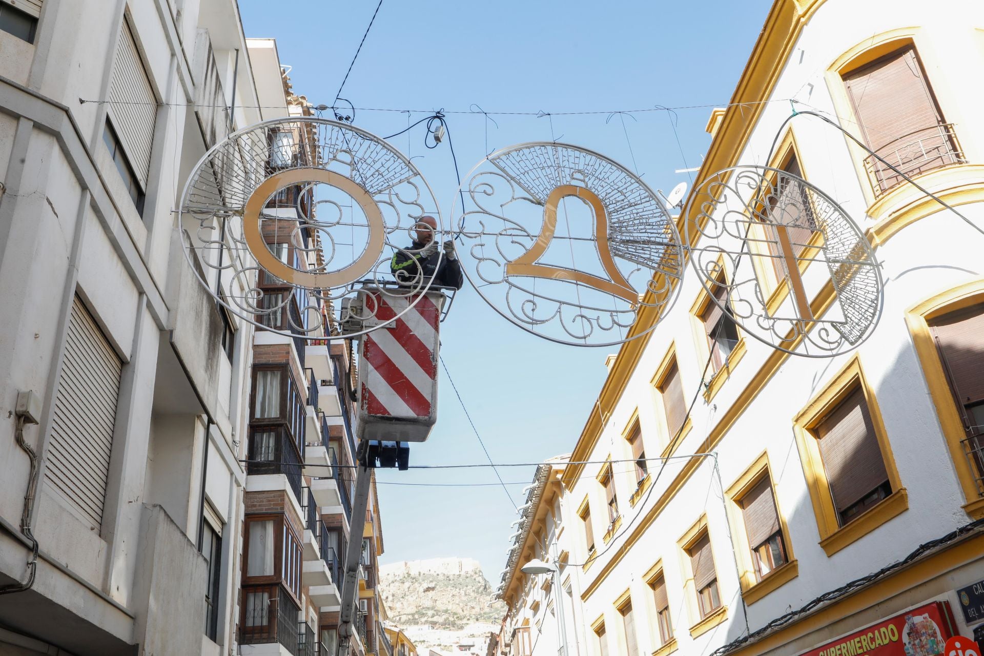Colocación de las guirnaldas con motivos navideños en la calle Álamo.