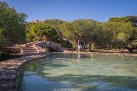 Dos turistas pasean junto al canal de agua que atraviesa el parque.