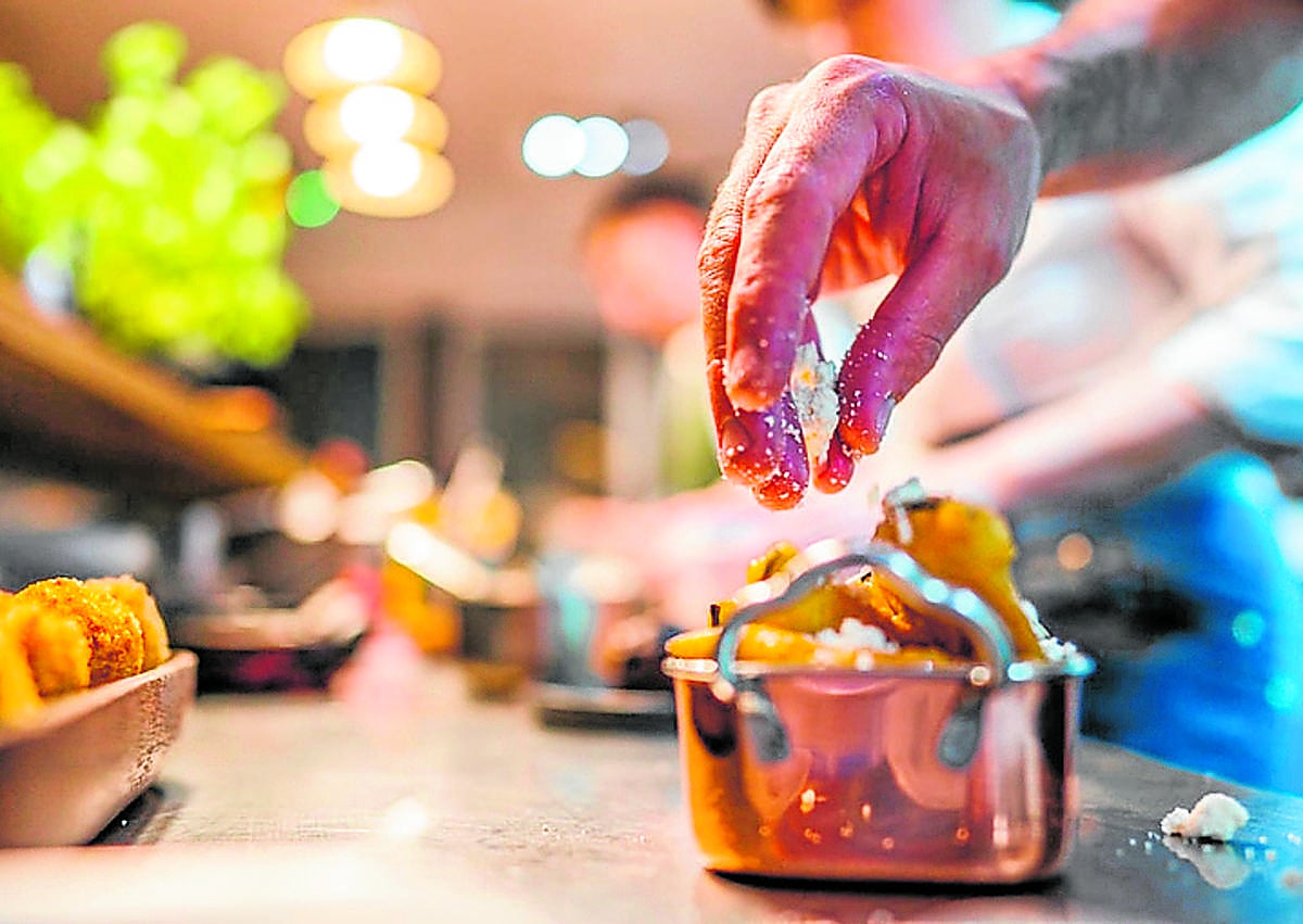 Imagen secundaria 1 - Arriba: Terraza de Ignis, en una de las características calles empedradas de la isla de Korcula. Abajo: Último toque a las berenjenas en tempura con miel OPG Komparak (de la isla) y queso de cabra local, Pilar ajusta el delantal a su pareja, Vicko.