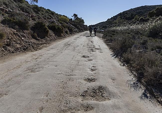 Dos senderistas pasean este martes por el camino con socavones.