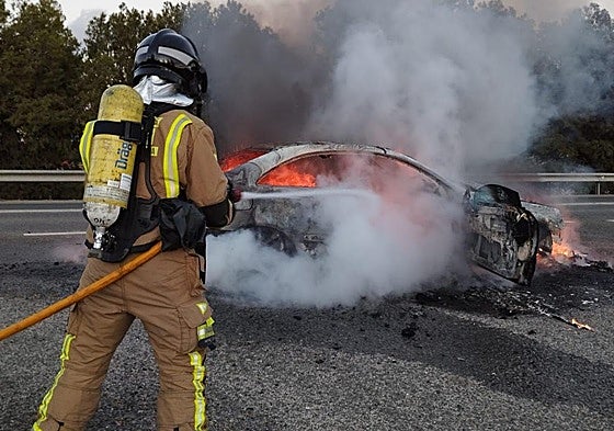 Un bombero trata de apagar el incendio originado en un coche, en una imagen de archivo.