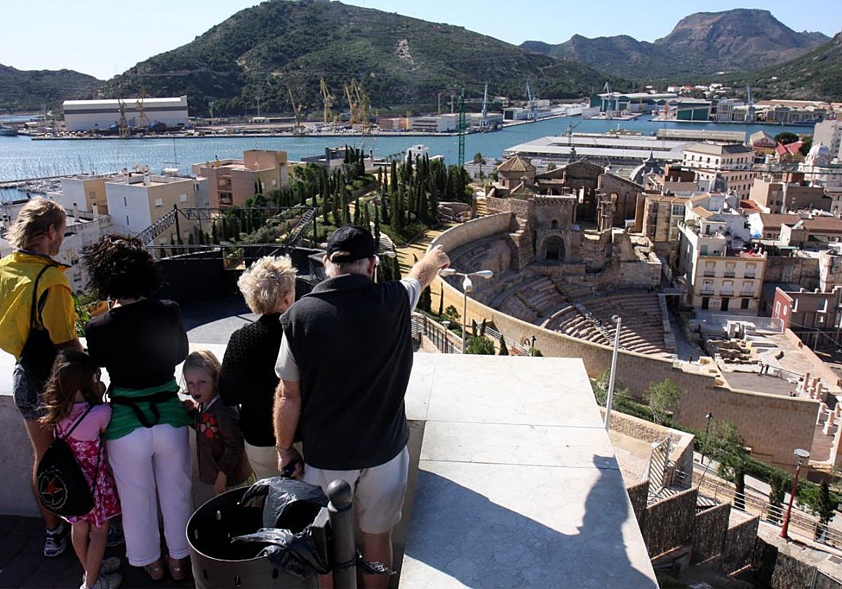 Un grupo de turistas observa el Teatro Romano y la dársena del puerto desde el mirador del Parque Torres.