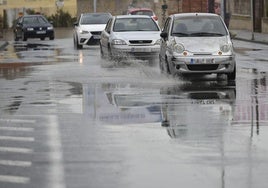 Coches circulan por una calle de Murcia encharcada por la lluvia, en una imagen de archivo.