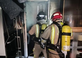 Dos bomberos en el interior de la vivienda incendiada.